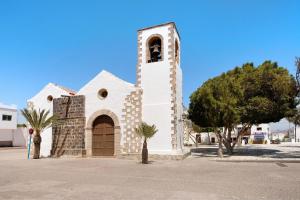 a small white church with a clock tower at Casa Valentina in Tuineje