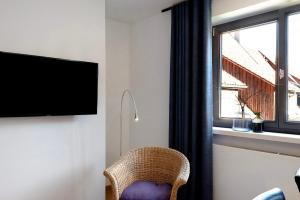 a living room with a wicker chair and a television at 1 Zimmer-appartment Nr 21 in Wangen im Allgäu