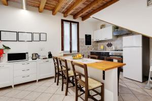 a kitchen with white cabinets and a wooden table at Il Vagabondo in Volta Mantovana