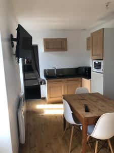 a kitchen with a wooden table with chairs and a dining room at Appartement T 2 in La Bourboule