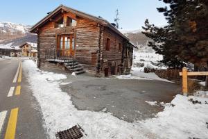 a log cabin in the snow next to a road at La Coccinella Livigno in Livigno