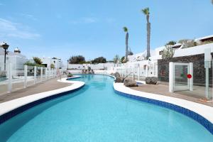 a swimming pool in a resort with blue water at Puerto Chico E in Playa Blanca