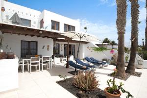 a house with a patio with chairs and an umbrella at Puerto Chico E in Playa Blanca