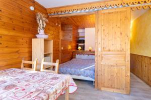 a bedroom with a bed and a wooden wall at L'Alpazen Jouve Studio Terrasse in Saint-Véran