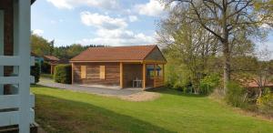 a small wooden cabin in a yard next to a house at 5 Chalet Iris in Blavignac
