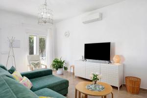 a living room with a green couch and a flat screen tv at La Casita de la Florida in Conil de la Frontera