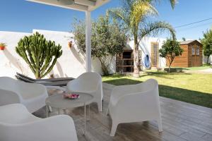 a patio with white chairs and a table at La Casita de la Florida in Conil de la Frontera