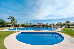 a large swimming pool with a blue pool at Luxury 3 Beds Villa Inside Resort in Estepona