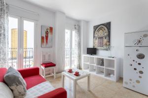 a white living room with a red couch and a table at Apartamento Pintada 25 in Nerja
