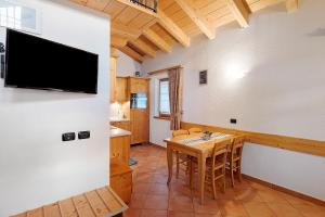 a dining room with a table and a tv on a wall at La Coccinella Livigno in Livigno