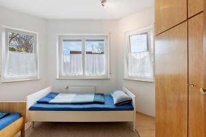 a small bedroom with a bed and two windows at Ferienwohnung Geiger in Volkertshausen