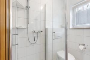 a white bathroom with a shower and a toilet at Ferienwohnung Geiger in Volkertshausen +17 photos