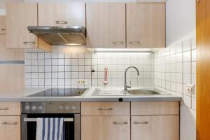 a kitchen with wooden cabinets and a sink and a stove at Ferienwohnung Geiger in Volkertshausen