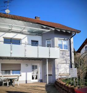 a white house with a balcony and a table at Ferienwohnung Geiger in Volkertshausen