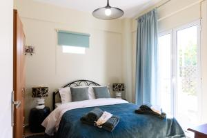 a bedroom with a bed with blue sheets and a window at Seaside House In Agios Vasilios in Patra