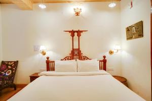 a bedroom with a large bed with white sheets at Danish Villa Heritage Property in Shimla +4 photos