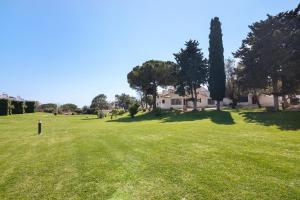 a large grass field with a house in the background at T0 Pedras Del Rei in São Pedro