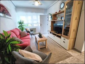 a living room with a red couch and a tv at R-15 Large Holiday House in Torrevieja