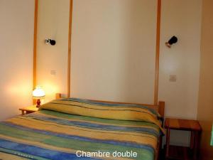 a bedroom with a bed with a striped blanket at 16 Chalet Hibiscus in Blavignac