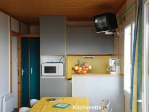 a small kitchen with a table and a microwave at 16 Chalet Hibiscus in Blavignac