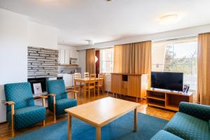 a living room with blue chairs and a table at Santa's Hotel Tunturi in Saariselka