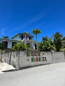 a retaining wall with a reggae rooster sign in front of a house at The Sandora Villa in Biladu