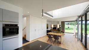 a kitchen and dining room with white cabinets and a wooden table at Ferienhaus Wreechen 25, Haus 2 in Putbus