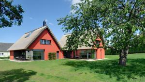 a red house with a thatched roof on a lawn at Ferienhaus Wreechen 25, Haus 2 in Putbus