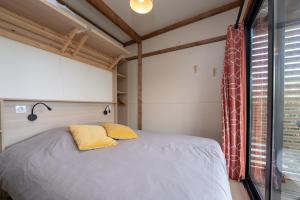 a bedroom with a bed with yellow pillows and a window at Chalet 30m2 - Ouessant in Plouhinec