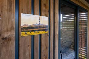 a picture hanging on a wooden wall with a window at Chalet 30m2 - Ouessant in Plouhinec