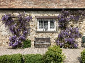a bench in front of a building with purple flowers at Chambre D'hôtes - Chambre in Jeufosse