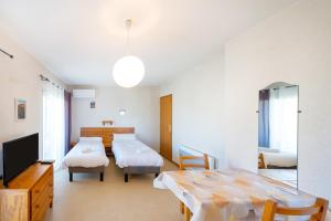 a room with two beds and a table and a tv at Les Mimosas - Appartement 09 in Cazaubon
