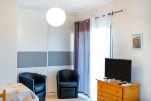 a room with two chairs and a television on a dresser at Les Mimosas - Appartement 09 in Cazaubon