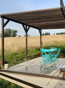 a table and chairs on a wooden deck with a roof at Gîte à la ferme- Chalet à la nuitée in Mazan-lʼAbbaye +20 photos