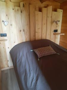 a bed in a room with wooden walls at Gîte à la ferme- Chalet à la nuitée in Mazan-lʼAbbaye
