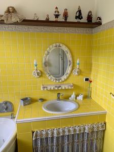 a yellow tiled bathroom with a sink and a mirror at Casa di Eli e Matte in Le Serucce +10 photos