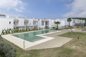 a swimming pool in front of a white building at Moderno Apartamento Atlanterra in Zahara de los Atunes
