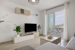 a living room with a flat screen tv on a white wall at Moderno Apartamento Atlanterra in Zahara de los Atunes