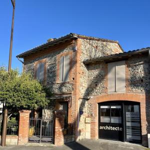 an old brick building with an antemedicate sign on it at Chambre d'hôtes oyasumi in Muret