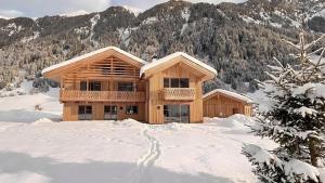 a log home in the snow with mountains in the background at Archerhof in Racines