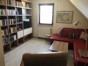 a living room with a red couch and book shelves at Haus Peeneblick in Freest