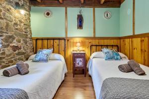 two beds in a room with wooden walls at Casa Rural Cornatel in Villavieja