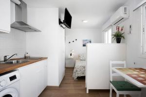 a small white kitchen with a sink and a table at Atico Juani in Conil de la Frontera +8 photos