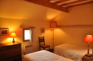 a bedroom with two beds and a chair and a window at Haras de la fontaine Datcha in Poligny