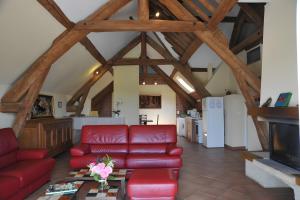 a living room with a red couch and a fireplace at Haras de la fontaine Datcha in Poligny