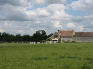 an old house in a field with a white fence at Haras de la fontaine Datcha in Poligny