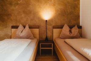 two beds with pillows sitting next to a lamp at Apartment Andreas - Gallhof in Vollan