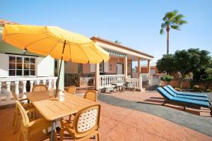 a wooden table with a yellow umbrella on a patio at Eveas - Villa with Pool in Tenerife in Candelaria