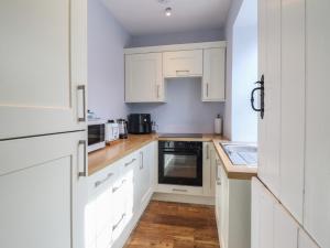 a white kitchen with white cabinets and a wooden floor at Glanrafon in Llwyngwril