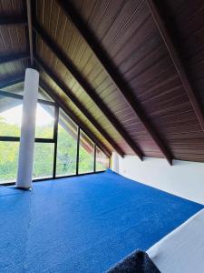 a large room with a blue bed with windows at Mirador Cottage in Bandarawela